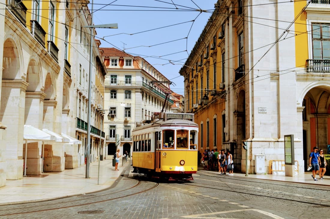 A yellow tram on a street in Lisbon